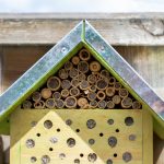 A small ecological insects hotel bug house with a wild bee on the right. Nature and insect friendly