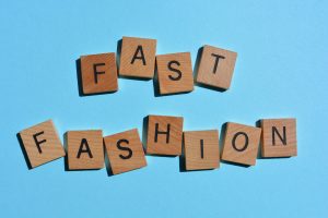 Fast Fashion, words in 3d wooden alphabet letters isolated on colourful background